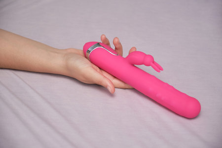 Unrecognizable woman holding a dildo in bedの写真素材