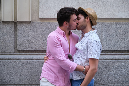 Young gay couple kissing at street.の写真素材