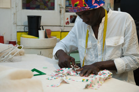 A tailor cutting fabric in his sewing shop. African man working in a workshop.