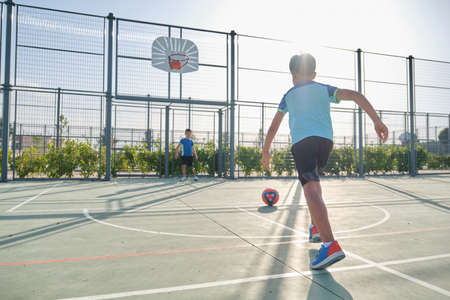 Two brothers playing football, one of them has a leg prosthesis and the other is kicking a penalty. Siblings playing sports together.の写真素材