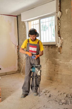 Young caucasian construction worker checking the jackhammer wire because it is not working.