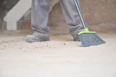 Close up of a young caucasian construction worker sweeping the floor at a construction site.