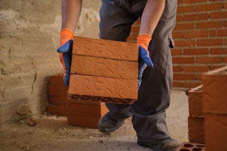 Close up of a young caucasian construction worker moving bricks at the construction site.