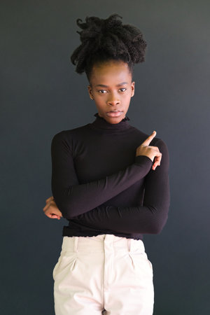 Young african woman wearing black sweater standing on a black background. Studio shot.の写真素材