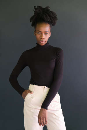 Young african woman wearing black sweater standing on a black background. Studio shot.の写真素材