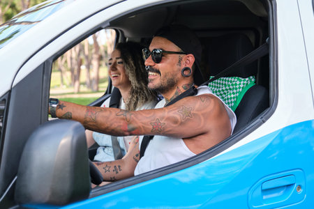 Young tattooed couple driving a van and laughing.
