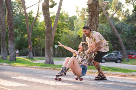 Young cool tattooed couple having fun skateboarding.の写真素材