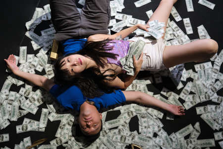 Died young asian couple surrounded by dollar bills. Suicide with a gunshot.の写真素材