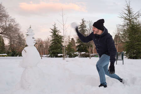 Young caucasian man destroying a smiley snowman with a hat.の写真素材