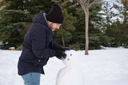 Young caucasian man making a snowmanの写真素材