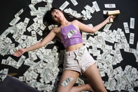 Died young asian woman surrounded by dollar bills. Suicide with a gunshot.の写真素材