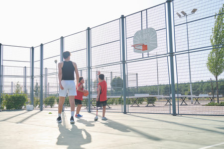 Three brothers playing basketball, one of them has a leg prosthesis.の写真素材