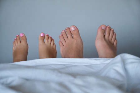 Mans and womans feet close-up in the bed.の写真素材
