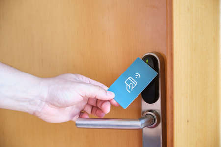 Male hand opening the hotel room electronic lock with a key card.の写真素材