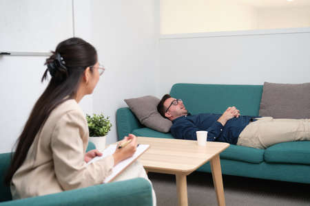 Asian female psychologist listening to her caucasian man patient.の写真素材