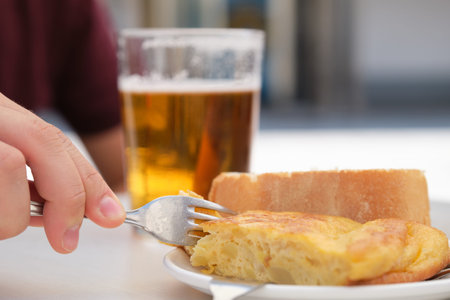 Hand taking a piece of Spanish omelette with a fork.
