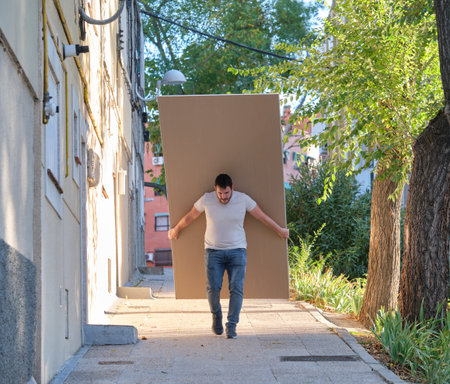 Young contractor carrying plasterboard sheets.