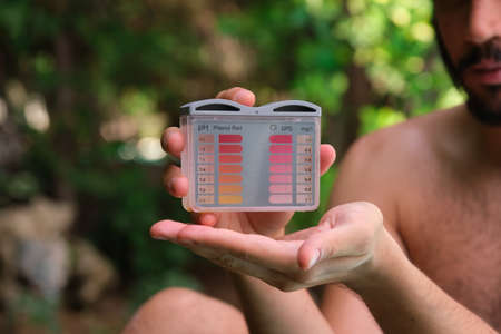 Unrecognizable man showing a ph and cl kit to the camera.の写真素材