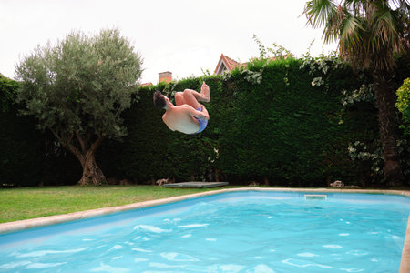 Young caucasian man jumping into the swimming pool.