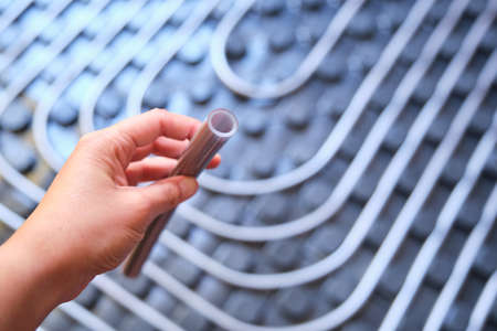 Hand holding a polyethylene pipe used for radiant underfloor system.の写真素材