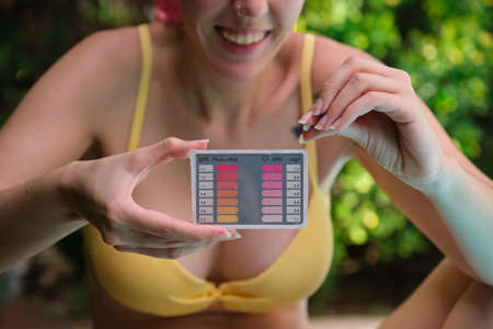 Young caucasian woman using a ph and cl kit to test the pool water quality.の写真素材