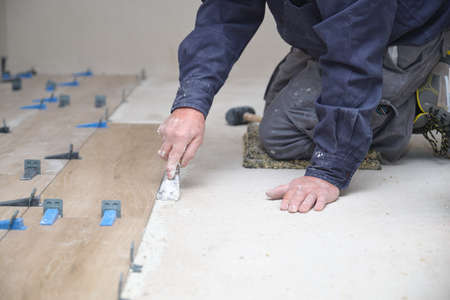Unrecognizable senior mason laying ceramic wood effect tiles.の写真素材