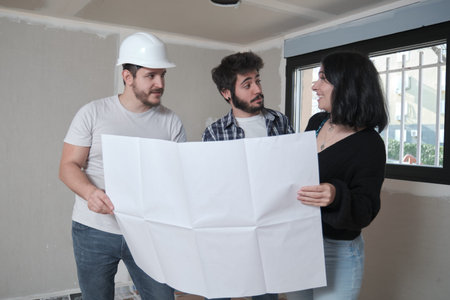 Architect shows apartment in construction blueprints to interested young couple.