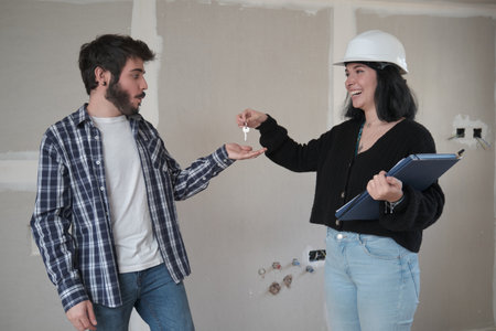 Young man receiving the keys of his new apartment in construction.の写真素材