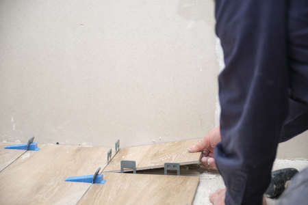 Unrecognizable senior mason laying ceramic wood effect tiles.の写真素材