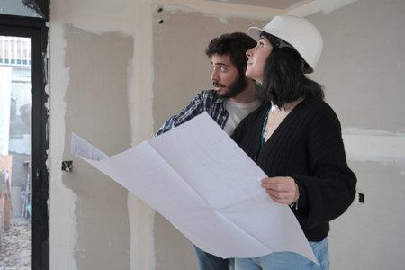 Female architect and worker discussing building plan at construction site.の写真素材