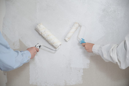 Unrecognizable young couple painting walls in their new house in construction.
