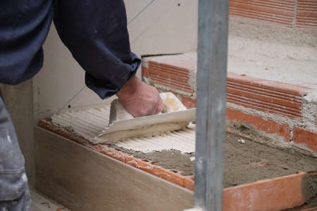 Unrecognizable bricklayer using a notched trowel to build a staircase in a home.の写真素材