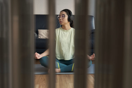 Young asian woman listening relaxing music and meditating doing the easy pose.