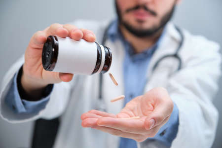 Unrecognizable doctor pouring pills from a bottle.の写真素材