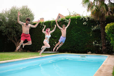 Group of three friends jumping into the swimming pool.の写真素材