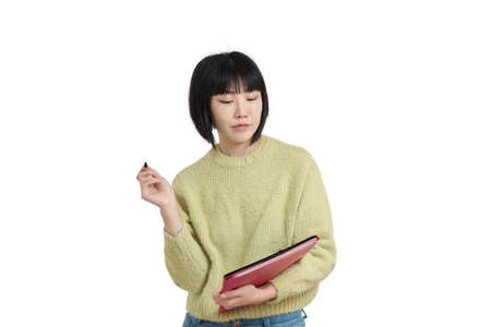 Young asian student woman writting on a paper, wearing winter green sweater, isolated on white background.の写真素材