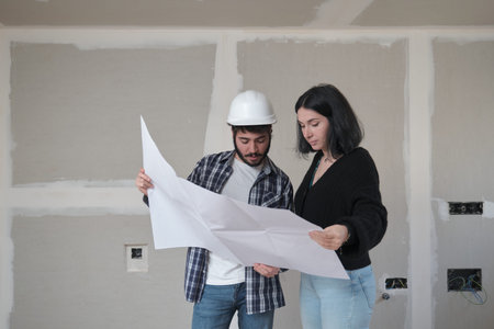 Female architect and construction worker discussing building plan at construction site.の写真素材