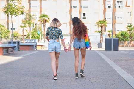 Young lesbian couple holding hands and walking backwards. LGBT relationship.の写真素材