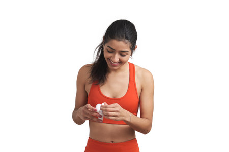 Young Venezuelan sportswoman smiling and wearing earphones. Isolated over white background.