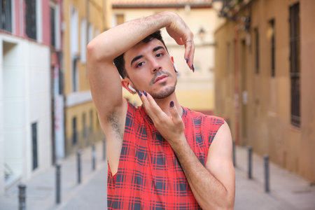 Portrait of a young caucasian man with long false nails doing poses with his arms.