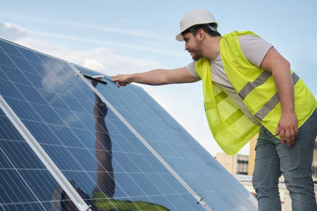 Technician washing solar panels with a squeegee window cleaner.の写真素材