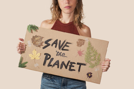 Woman holding a handmade cardboard with an inscription: Save the planet.