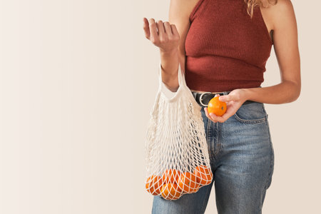 Unrecognizable woman holding shopping cotton mesh eco bag with tangerines. Zero waste concept.の写真素材