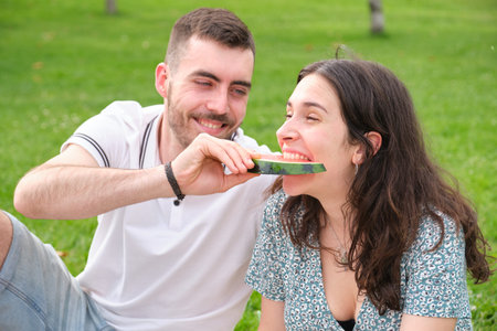 Happy young couple holding a piece of watermelon, the boyfriend is giving watermelon to his...