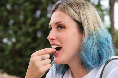 Young happy woman eating a blueberry in a park. Picnic on a sunny summer day.の写真素材
