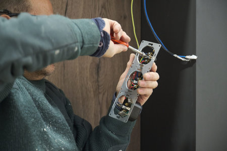 Close up of a man hands unscrew power socket with screwdriver to connect wires.