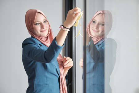 Muslim woman using sticky notes on windows to plan a marketing strategy in meeting room.の写真素材