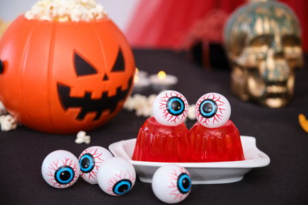 Halloween snacks table with eyeballs on red jelly and pumpkin with popcorn. Sweets for Halloween party.の写真素材