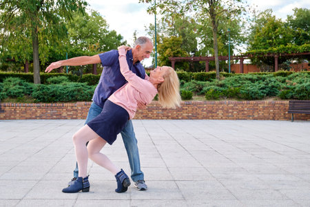 Mature happy couple dancing tango in a park at street.の写真素材