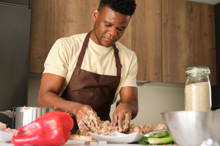 Young black man preparing a chicken mince recipe in a kitchen.の写真素材